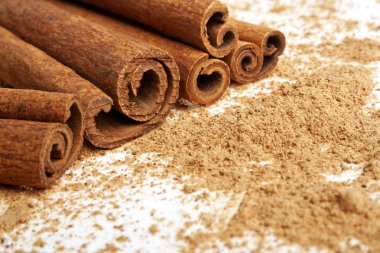 Tarçın ile onun etrafında toz beyaz bir arka plan üzerinde sopa