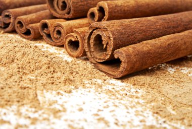 Tarçın ile onun etrafında toz beyaz bir arka plan üzerinde sopa