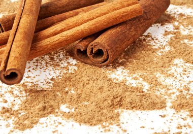 Tarçın ile onun etrafında toz beyaz bir arka plan üzerinde sopa