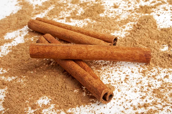 Cinnamon sticks with its dust around it over a white background