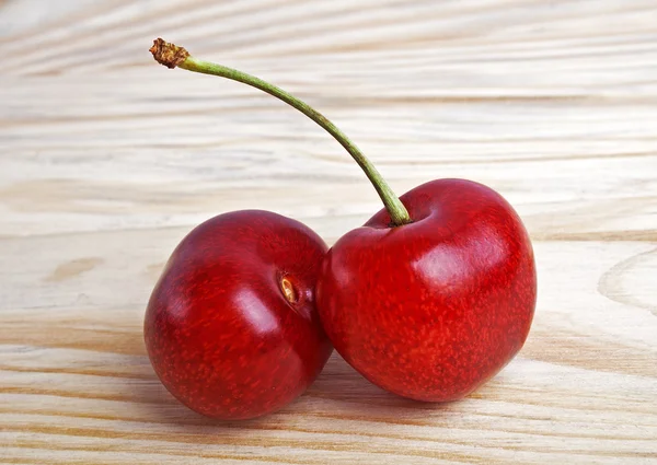 Dos bayas de cereza aisladas sobre fondo de madera — Foto de Stock