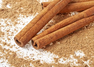 Tarçın ile onun etrafında toz beyaz bir arka plan üzerinde sopa