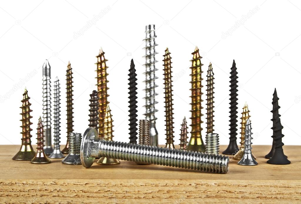 Various screws on wooden plank on a white background