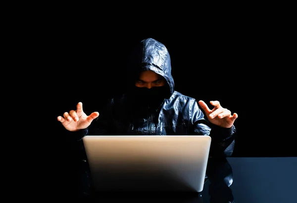 anonymous hacker with laptop in the dark. technological crime concept