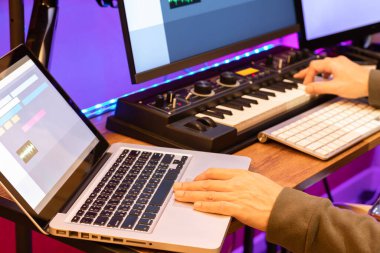male composer, producer, arranger, song writer, musician hands arranging music on computer in home studio. music production concept clipart