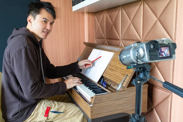 アジア系の若いハンサムな音楽インストラクターが自宅で学生を教えながらライブビデオをストリーミングします Eラーニング技術の概念は — ストック写真