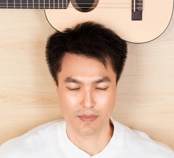 清潔で健康な肌を示す若いアジアのハンサムな男の肖像 アコースティックギターで昼寝 — ストック写真
