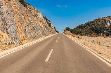 Tepeye giden otoyol. Dağ ve orman, güneş ışığı yolu. Arabadan görüntü.