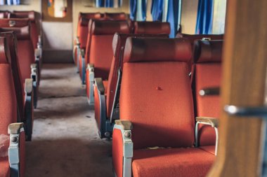 Terk edilmiş tren kamarası, içinde kırmızı hasarlı koltuk var..