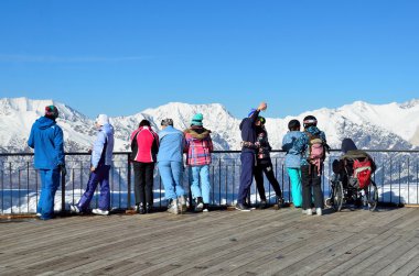 Sochi, Russia, February, 29, 2016, Ski resort Rosa Khutor. People look for the mountains from the observation deck of Rosa peak clipart