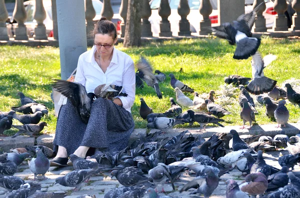 Moskau, russland, 21. august 2016. frau füttert tauben im sommer auf dem iljinski-platz — Stockfoto