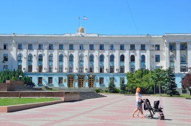 Simferopol, Kırım'da, Temmuz, 14, 2016. Kırım Cumhuriyeti Hükümeti binada yaz Lenin Meydanı üzerinde yürüyen bir bebek arabası olan kadın