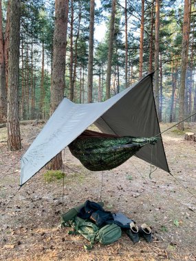Orekhovo-Zuyevsky district, Moscow region, Russia, April, 17, 2021. Meschera, a tourist sleeps in a hammock in the spring forest clipart