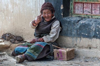 TIBET, ÇİN - 23 AĞUSTOS 2018: Kimliği belirsiz yaşlı Tibetli kadın Pasum köyü, Tibet 'teki bir binanın önünde oturuyor