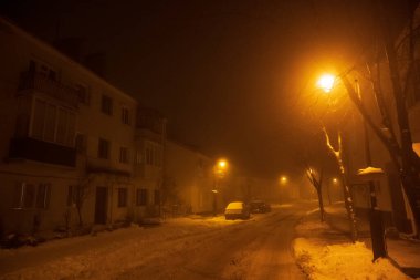 Şehir bir kış kasabasında ışık saçıyor. Sisli ve karlı bir hava. Beyaz karla kaplı ağaçlar