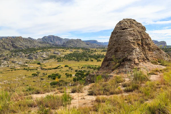 Steep sharp rocks surrounding a valley with trees and grassland — Stock Photo, Image