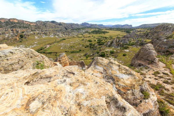 Steep sharp rocks surrounding a valley with trees and grassland — Stock Photo, Image