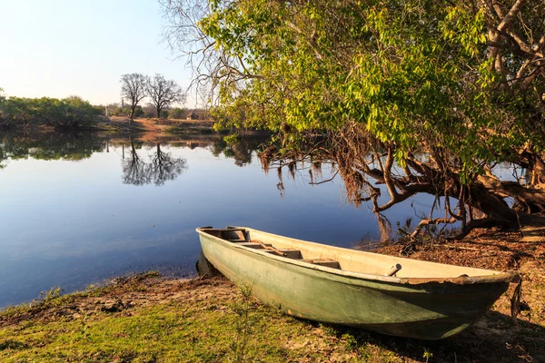 Bateau d'aviron couché sur les rives d'une rivière éclairée par le soleil — Photo