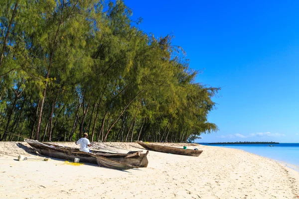 Fisherman repairing his traditional boat lying near on the beach — Stock Photo, Image