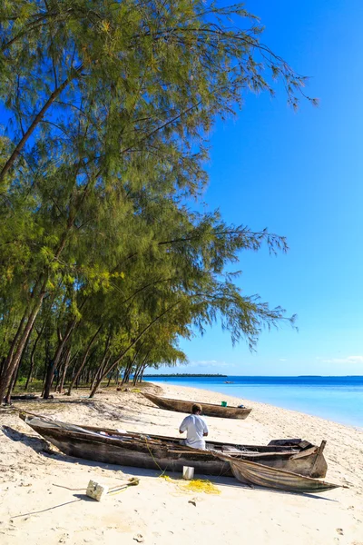 Fisherman repairing his traditional boat lying near on the beach — Stock Photo, Image