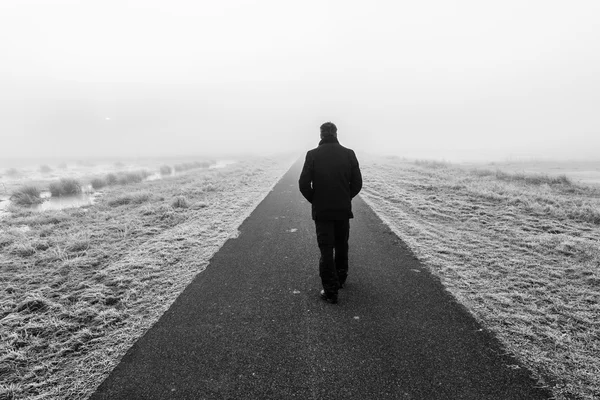 Homem caminhando em uma raod desolada vazia — Fotografia de Stock