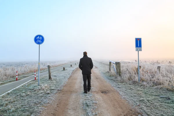 Man walking na piasku drogi w pejzażu zimowym — Zdjęcie stockowe