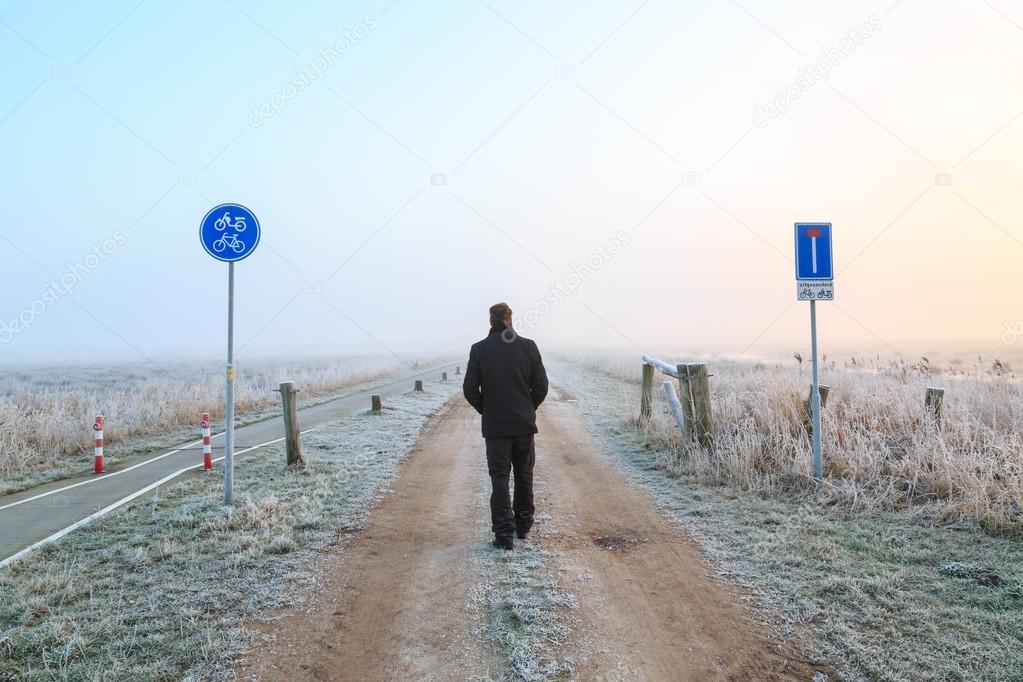 Man walking on a sand road in a winter landscape