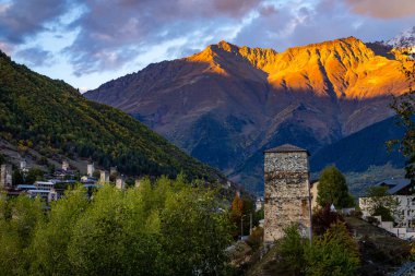 Tipik kule evleri olan Mestia köyünün günbatımı manzarası. Yukarı Svaneti, Georgia. Arkaplanda altın dağlar