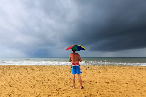 Man at the beach with dark clouds above the ocean — Stock Photo, Image