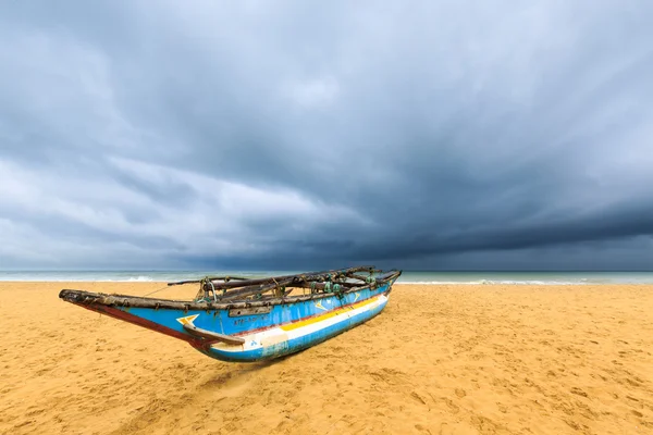 Barco de pesca en la playa con nubes oscuras sobre el océano Fotos de stock libres de derechos