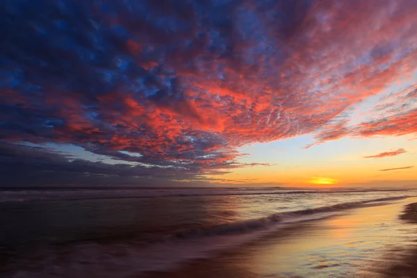 Beautiful colored clouds at the beach at sunset — Stock Photo, Image