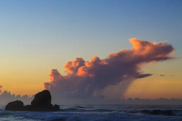 Alba su una spiaggia rocciosa con nuvole viola — Foto Stock