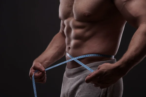Hombre midiendo su cintura con una cinta métrica —  Fotos de Stock