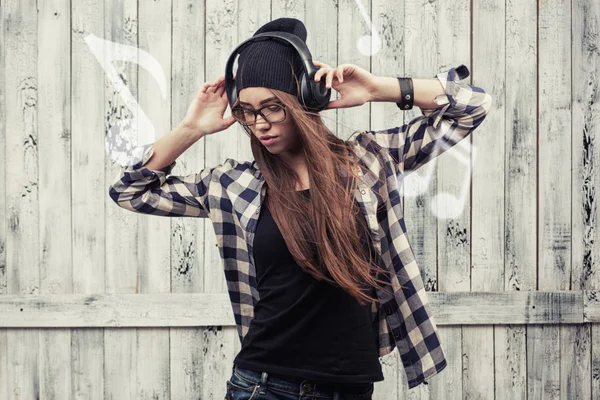 Menina em óculos, fones de ouvido e gorro preto — Fotografia de Stock