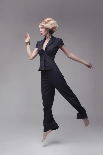 Модное фото прыгающей женщины в черном костюме — стоковое фото