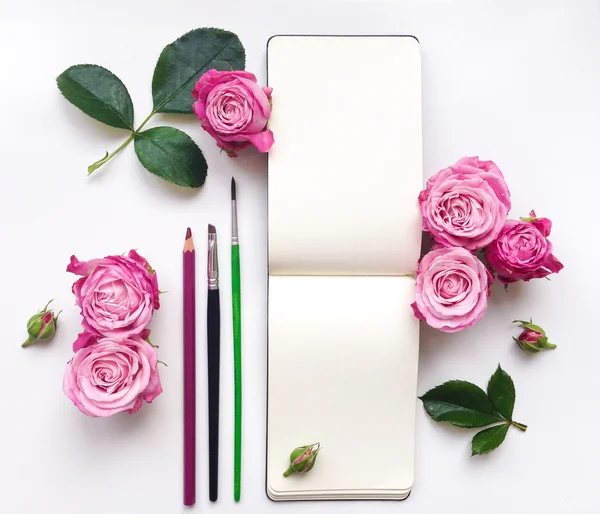 Colorful composition with sketchbook, roses and pencils. Flat lay — Stock Photo, Image