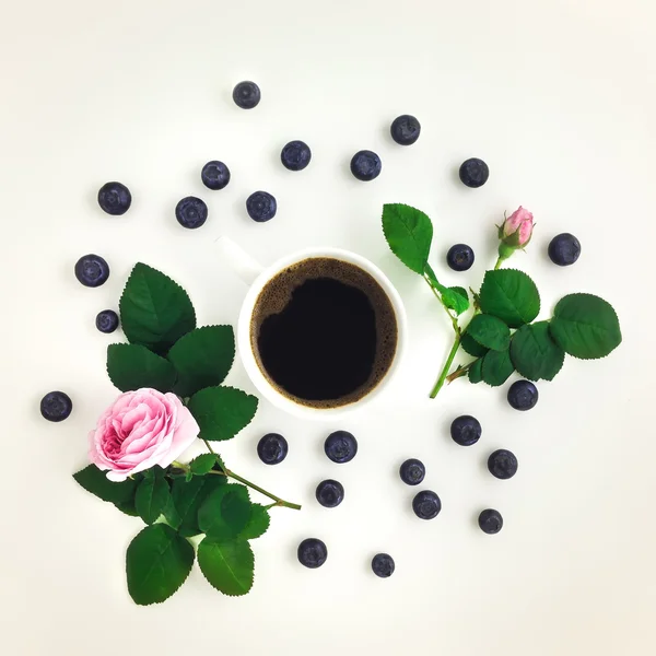 Taza de café negro y ramas de rosas aisladas sobre fondo blanco. Piso tendido, vista superior — Foto de Stock