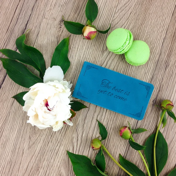 Bovenaanzicht van houten tafel met notebook, groene macarons en bloemen. Platte lat, weergave van bovenaf — Stockfoto