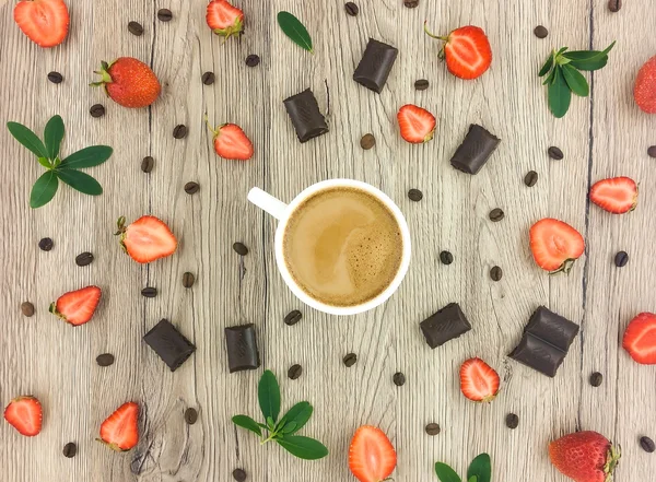 Kopp kaffe med mjölk, choklad och jordgubbar på trä bakgrund. Lägenheten låg, top view — Stockfoto