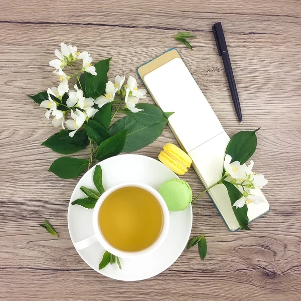 Composición de primavera de la taza de té, cuaderno y flores en la mesa de madera, la puesta plana —  Fotos de Stock