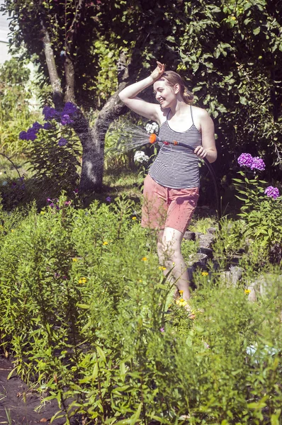 Stanco ma sorridente ragazza annaffiare le piante — Foto Stock