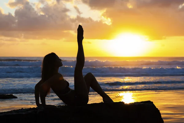 Fit femme étirant sur la plage au lever du soleil — Photo