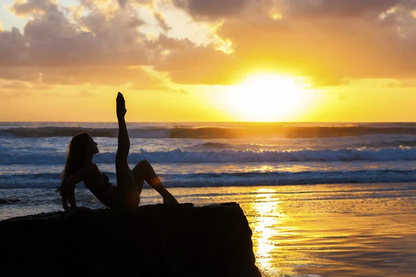 Vältränad kvinna stretching på stranden vid soluppgången — Stockfoto