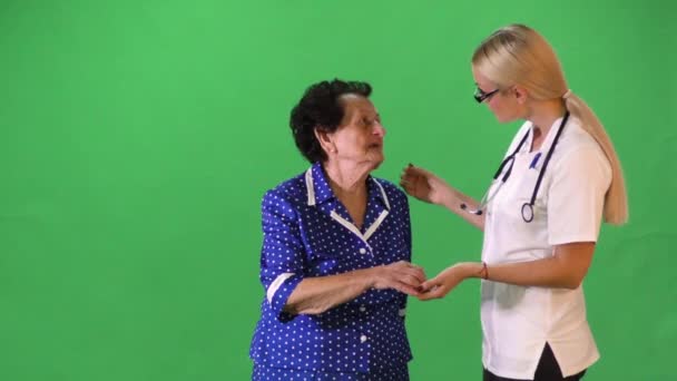 Jovem enfermeira atraente segurando a mão velha senhora . — Vídeo de Stock