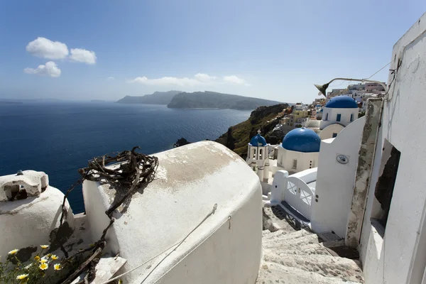Uma igreja ortodoxa grega branca pequena com um telhado azul típico no penhasco em Oia (Ia), ilha de Santorini, Cyclades Greece — Fotografia de Stock