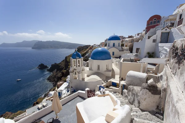 Uma igreja ortodoxa grega branca pequena com um telhado azul típico no penhasco em Oia (Ia), ilha de Santorini, Cyclades Greece — Fotografia de Stock