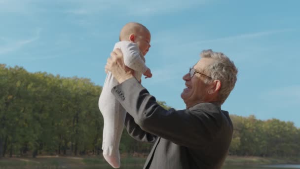 外で子供を抱えている祖父。孫との壮大な親戚関係. — ストック動画