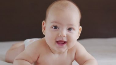 Küçük güzel kızın gülümsemesinin yavaş çekimini kapat. Bebek gülümsemesinin kapalı mekândaki portresi..