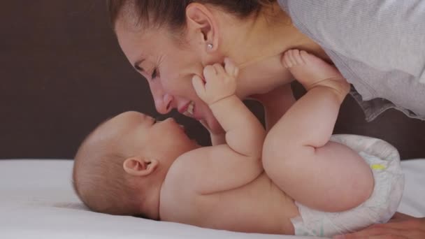 Blisko matka całuje szczęśliwe dziecko śmiejąc się kochający mama pielęgnując malucha w domu. — Wideo stockowe