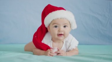 Mutlu Noeller ve mutlu yıllar, çocukluk, tatil konsepti yakın çekim. Noel Baba şapkalı yeni doğmuş 3 aylık bebek karnında emekliyor..